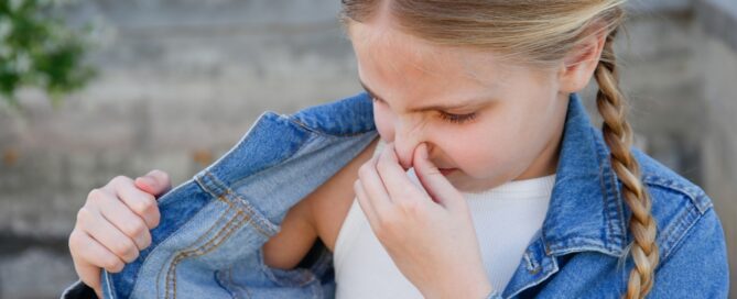 Young Girl Smelling Body with crinkled nose.