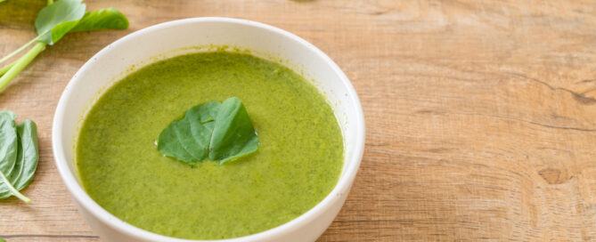 Green soup with leafy greens on top.